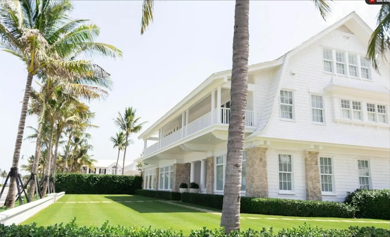 Two-story South Florida home with white siding, lawn and coconut palms