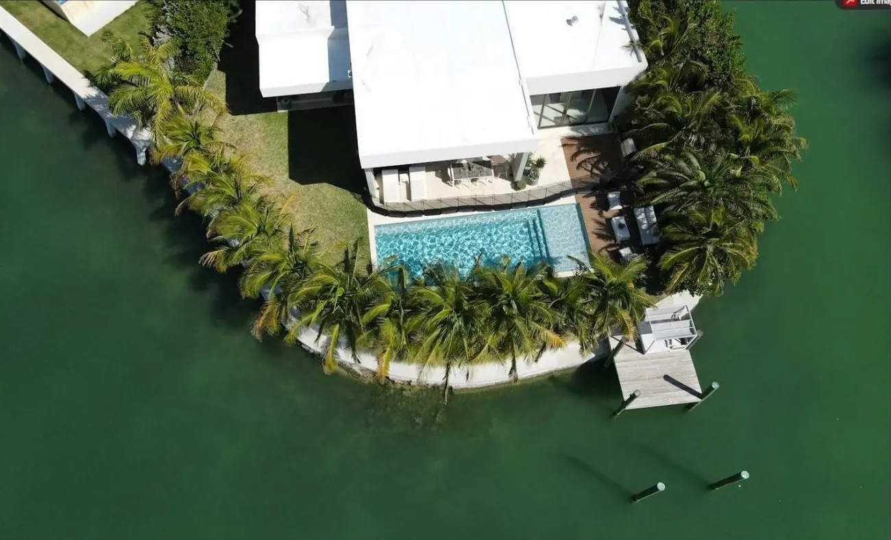 Aerial view of a modern waterfront home with pool and dock