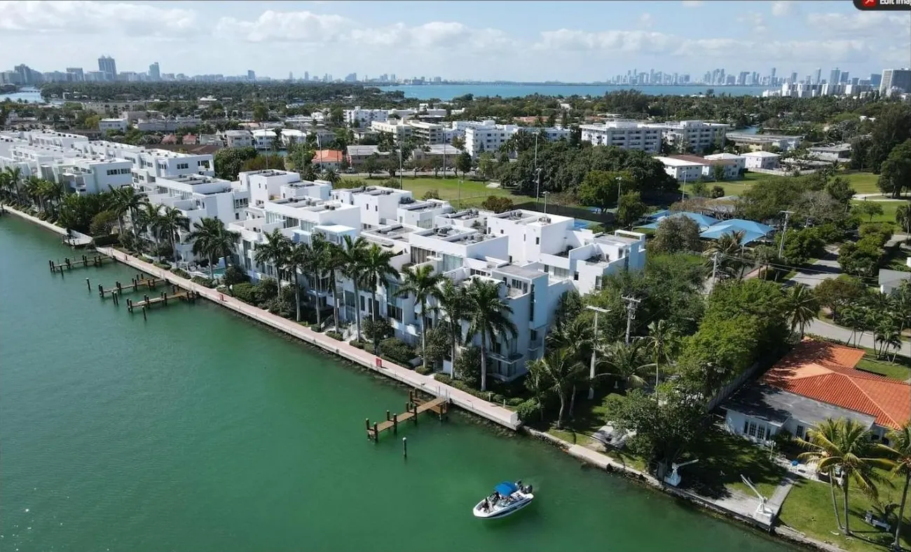 Aerial view of waterfront townhomes and single-family homes with the Miami skyline behind